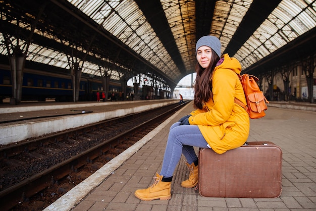 Jonge mooie vrouw die op de trein op het treinstation wacht, zit op