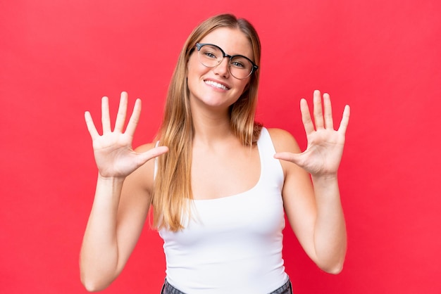 Jonge mooie vrouw die op rode achtergrond wordt geïsoleerd die tien met vingers telt