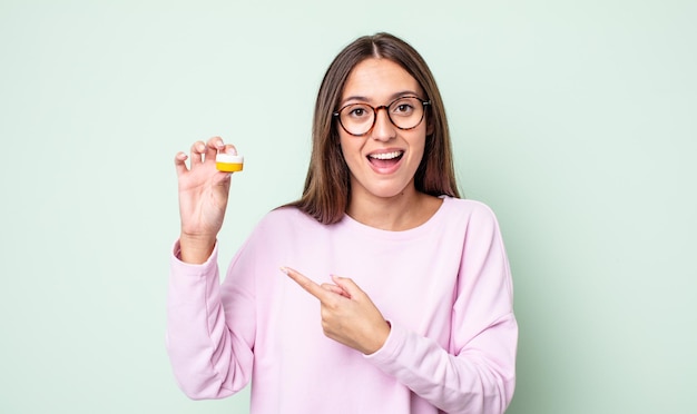 Jonge mooie vrouw die opgewonden en verrast kijkt en naar de zijkant wijst. contactlenzen concept