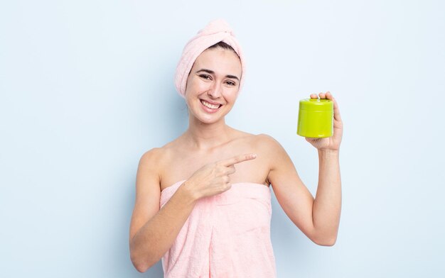 Jonge mooie vrouw die opgewonden en verrast kijkt en naar de zijkant wijst. douche- en haarproductconcept