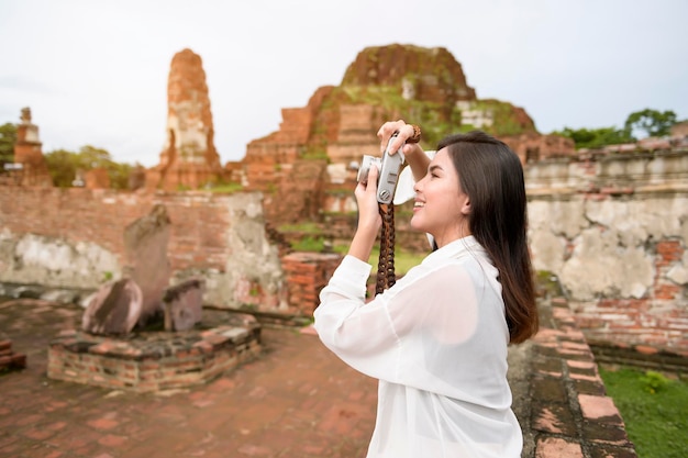 Jonge mooie vrouw die reist en foto's neemt in het thaise historische park