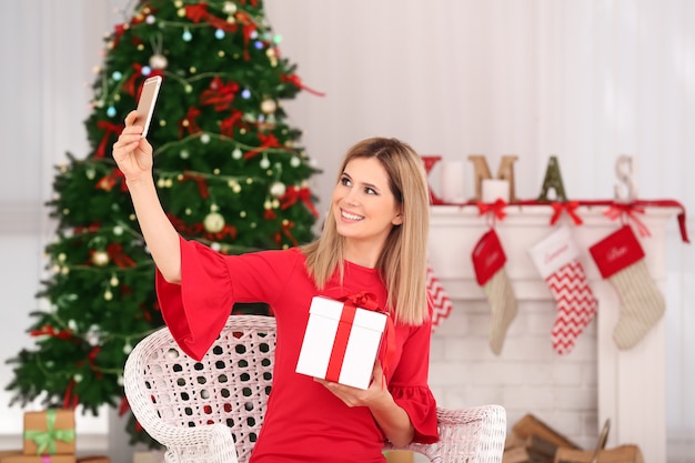 Jonge mooie vrouw die selfie neemt in de kamer die is ingericht voor Kerstmis