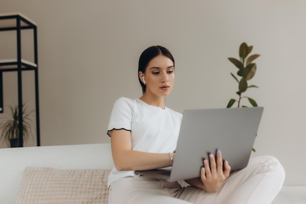 Jonge mooie vrouw die thuis een lap top computer met behulp van