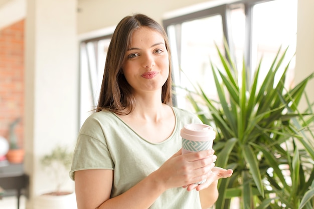 Jonge mooie vrouw die thuis koffie drinkt