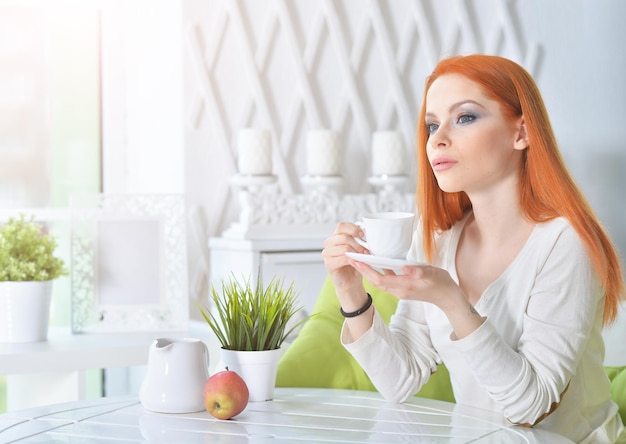 Jonge mooie vrouw die thuis koffie drinkt