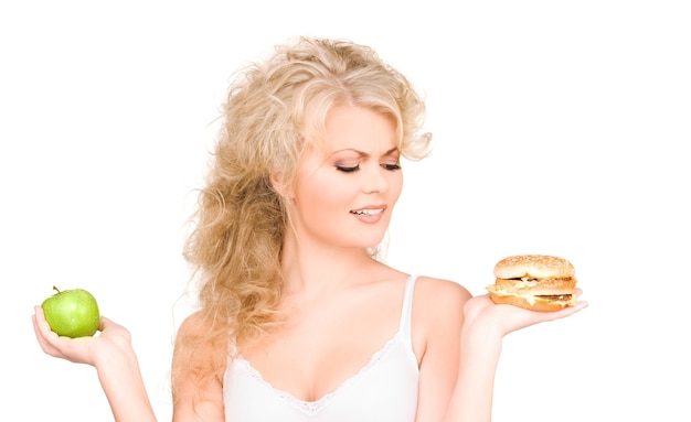 jonge mooie vrouw die tussen hamburger en appel kiest