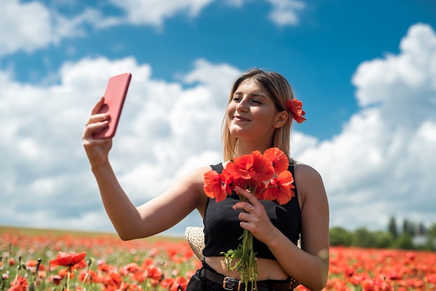 Jonge mooie vrouw die van de zomertijd op het gebied van de papaversbloem geniet. vrijheid