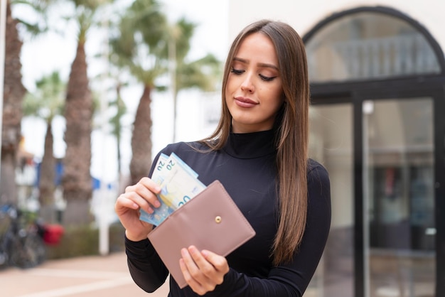 Jonge mooie vrouw die veel geld meeneemt naar buiten