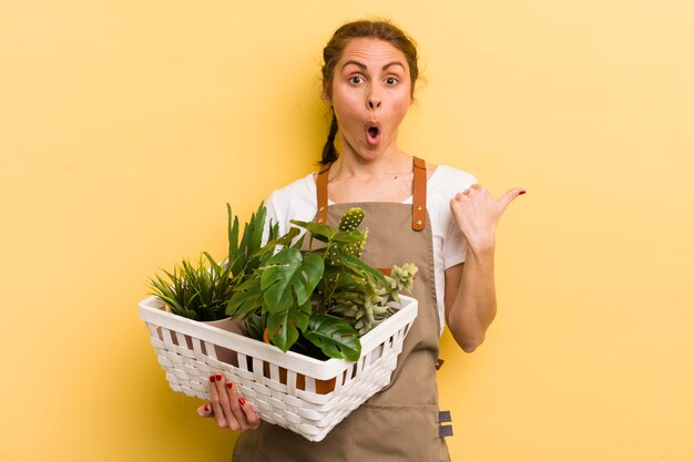 Jonge mooie vrouw die verbaasd kijkt in het concept van ongeloofplanten