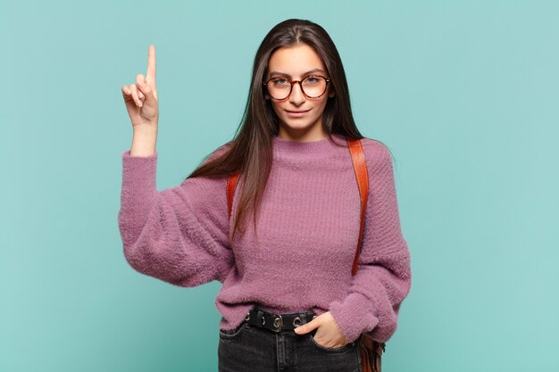 Jonge mooie vrouw die vrolijk en gelukkig lacht en met één hand naar boven wijst om ruimte te kopiëren