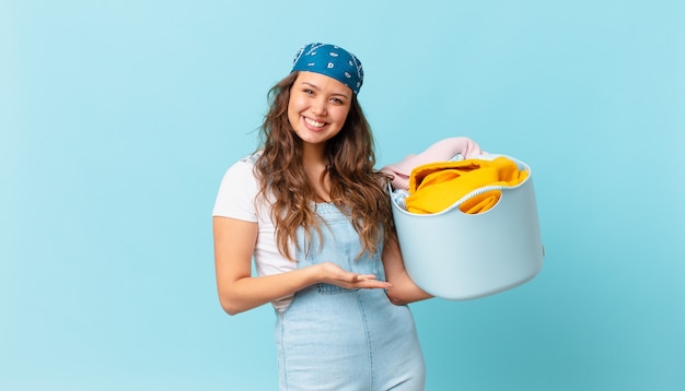 Jonge mooie vrouw die vrolijk lacht, zich gelukkig voelt en een concept toont en een wasmand vasthoudt