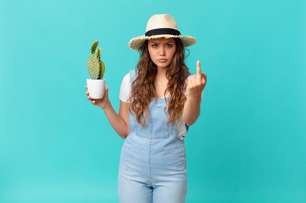 Jonge mooie vrouw die zich boos, geïrriteerd, opstandig en agressief voelt en een cactus vasthoudt