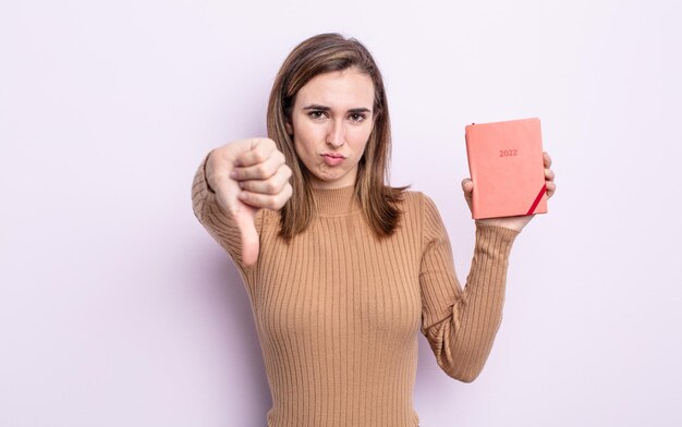 Jonge mooie vrouw die zich boos voelt en duimen naar beneden laat zien. agenda concept