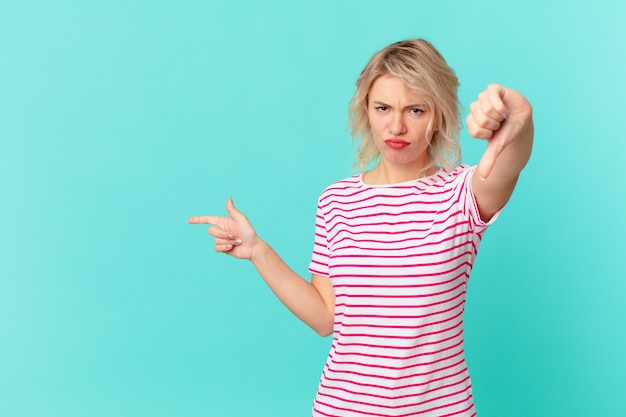 Foto jonge mooie vrouw die zich boos voelt en duimen naar beneden laat zien. kopieer ruimteconcept