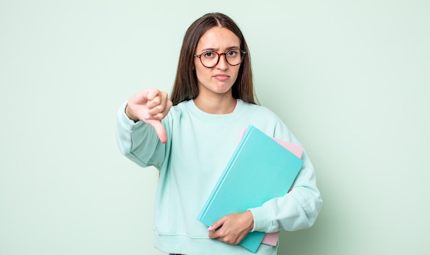 Jonge mooie vrouw die zich boos voelt en duimen naar beneden laat zien. universitaire student