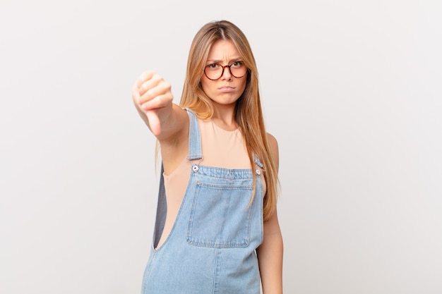 Jonge mooie vrouw die zich boos voelt en duimen naar beneden laat zien