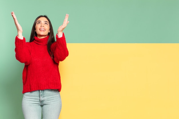 Jonge mooie vrouw die zich gelukkig, verbaasd, gelukkig en verrast voelt en de overwinning viert met beide handen in de lucht. kopieer ruimte om uw concept te plaatsen