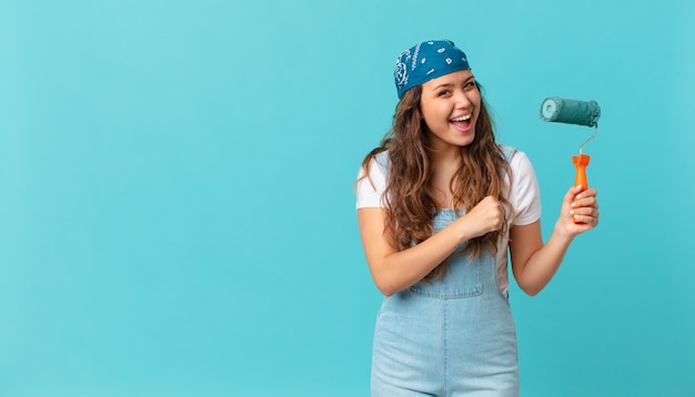 Foto jonge mooie vrouw die zich gelukkig voelt en een uitdaging aangaat of een muur viert en schildert