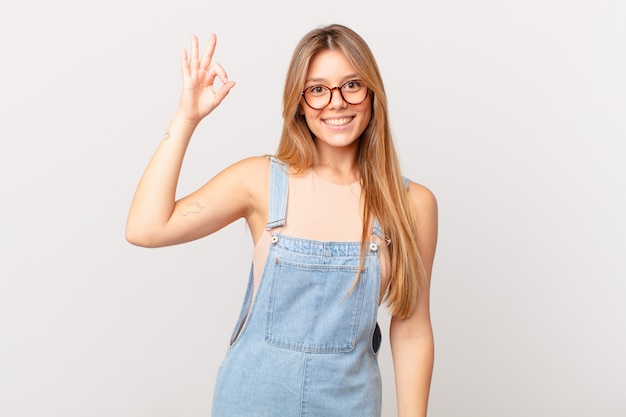 Jonge mooie vrouw die zich gelukkig voelt, goedkeuring toont met een goed gebaar