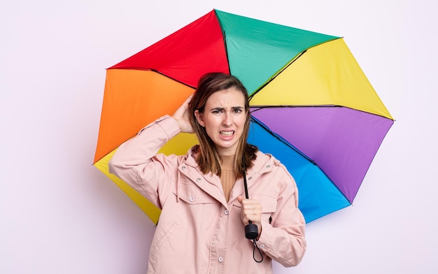 Jonge mooie vrouw die zich gestrest, angstig of bang voelt, met de handen op het hoofd. paraplu concept