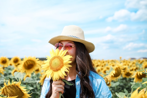 Jonge mooie vrouw die zich in zonnebloemgebied bevindt