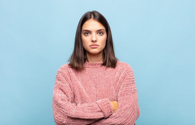 Jonge mooie vrouw die zich ontevreden en teleurgesteld voelt, ernstig, geïrriteerd en boos kijkt met gekruiste armen