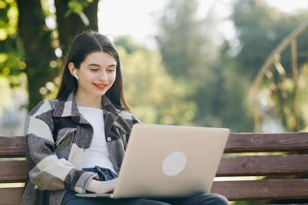 Jonge mooie vrouw die zich op een bank bevindt die laptop met behulp van