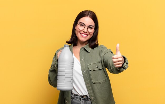 Jonge mooie vrouw die zich trots, zorgeloos, zelfverzekerd en gelukkig voelt, positief glimlacht met omhoog duimen