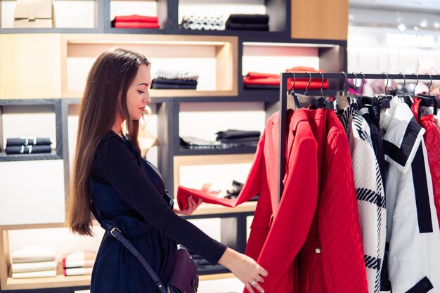 Jonge mooie vrouw die zichzelf nieuwe kleren vindt in een winkel supermarkt winkel