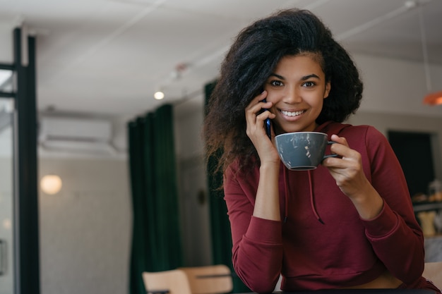 Jonge mooie vrouw drinken koffie in moderne café, met smartphone, communicatie. koffiepauze