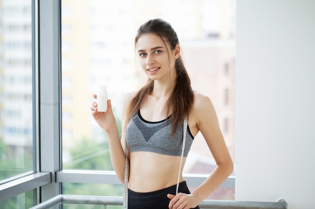 Jonge mooie vrouw drinken uit plastic fles yoghurt.