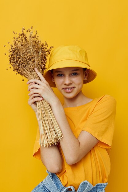 Jonge mooie vrouw een boeket gedroogde bloemen in handen jeugdstijl vrijetijdskleding gele achtergrond