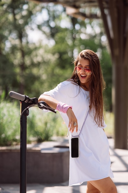 Jonge mooie vrouw en een elektrische scooter, ecologisch vervoer