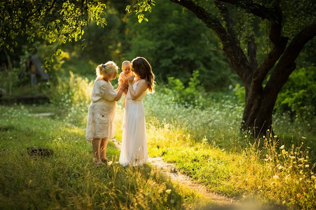 Jonge mooie vrouw en oude vrouw spelen met een klein kind buiten