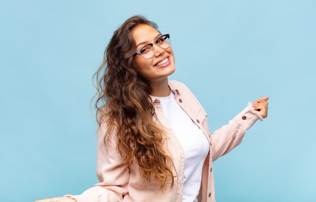 jonge mooie vrouw gebaren op blauwe muur