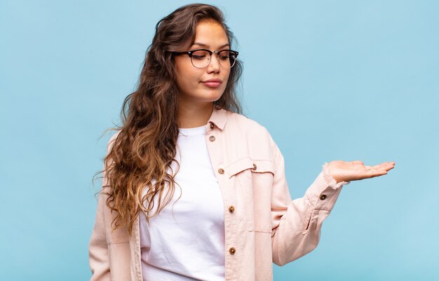 Jonge mooie vrouw gebaren op blauwe muur