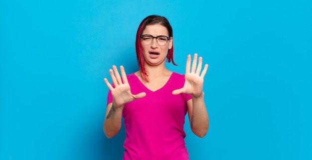 Jonge mooie vrouw gebaren op gekleurde muur