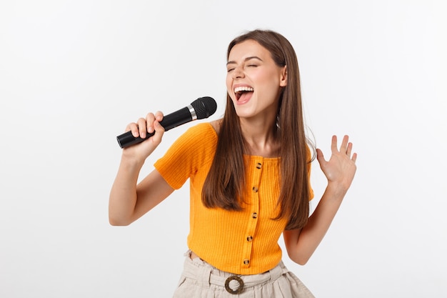 Jonge mooie vrouw gelukkig en gemotiveerd, zingt een lied met een microfoon, presenteert een evenement of heeft een feest, geniet van het moment