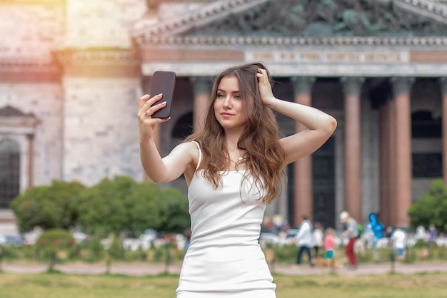 Jonge mooie vrouw glimlachend en selfie maken op telefoon in de buurt van sightseeing