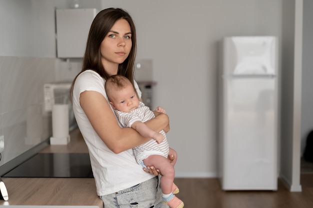 Jonge mooie vrouw houdt een klein kind in haar armen. Verlof voor kinderopvang. Gelukkige familie, plaats voor tekst.