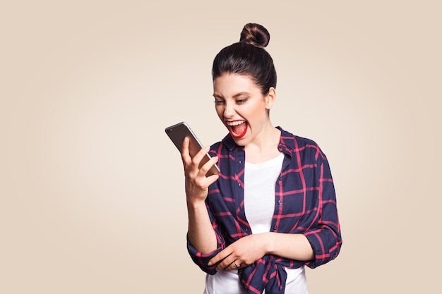 Jonge mooie vrouw in casual stijl schreeuwen op de telefoon. studio-opname op beige achtergrond.