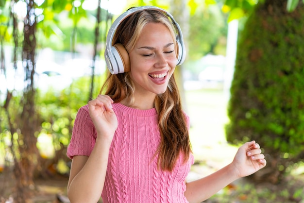 Jonge mooie vrouw in de buitenlucht luisteren naar muziek en dansen