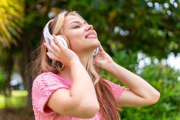 Jonge mooie vrouw in de buitenlucht luisteren naar muziek