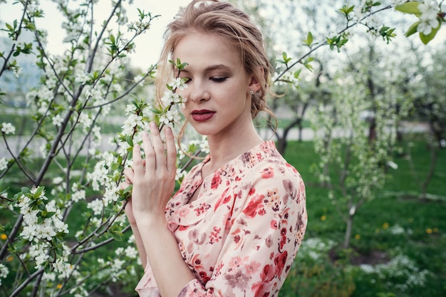 Jonge mooie vrouw in de kers-bloeiende tuin.
