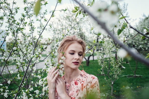 Jonge mooie vrouw in de kersenbloesemtuin Het gezicht van een vrouw is verborgen door witte bloemen en kersentakken Lente natuur Zoet aroma Bloeiende lente kersenboom Zoete geurige geur