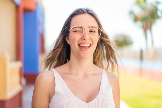 Jonge mooie vrouw in de open lucht met een bril en een gelukkige uitdrukking.