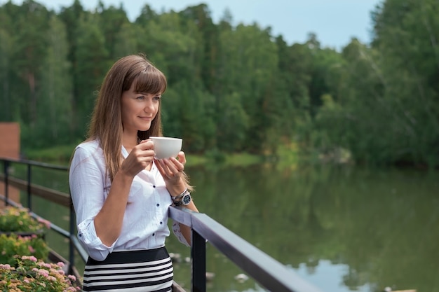 Jonge mooie vrouw in een zomerterras aan de rivier