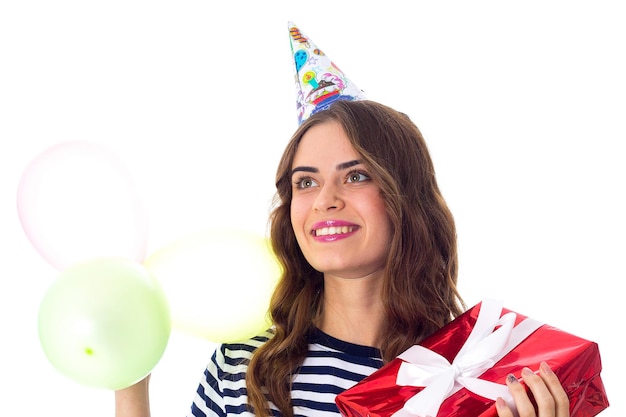 Jonge mooie vrouw in gestript T-shirt en feestmuts met cadeau en gekleurde ballonnen