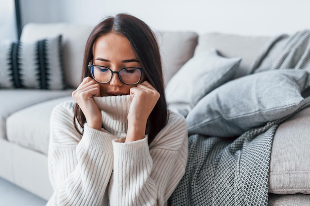 Jonge mooie vrouw in glazen om alleen thuis te zitten.