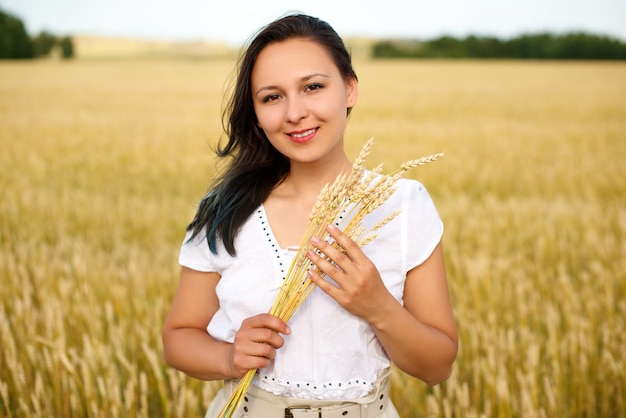 Jonge mooie vrouw in gouden tarweveld. concept van zomer, vrijheid, warmte, oogst, landbouw